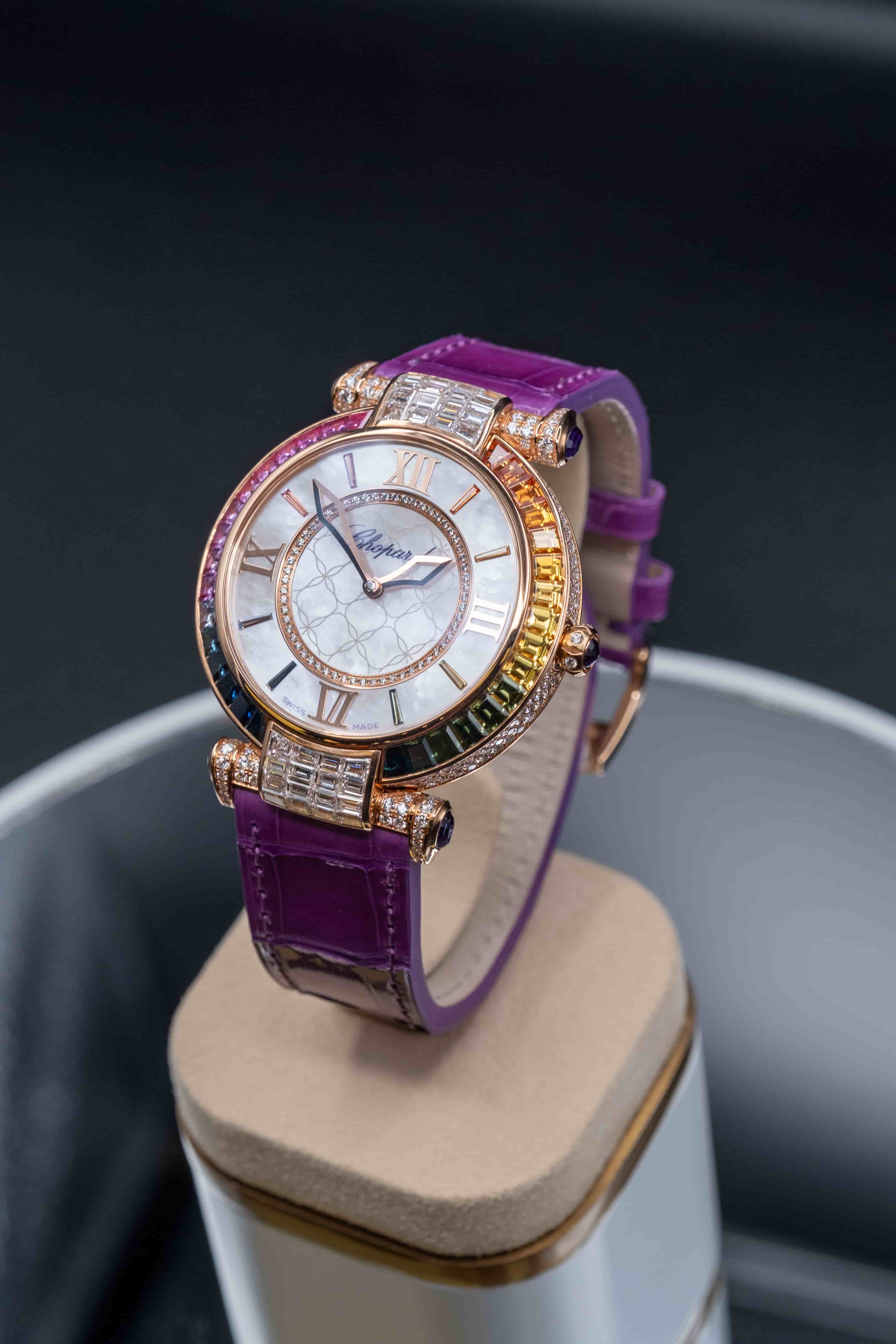 Close-up of a Chopard Imperiale watch featuring a purple alligator strap, diamond-set bezel, and a rainbow of precious gemstones.